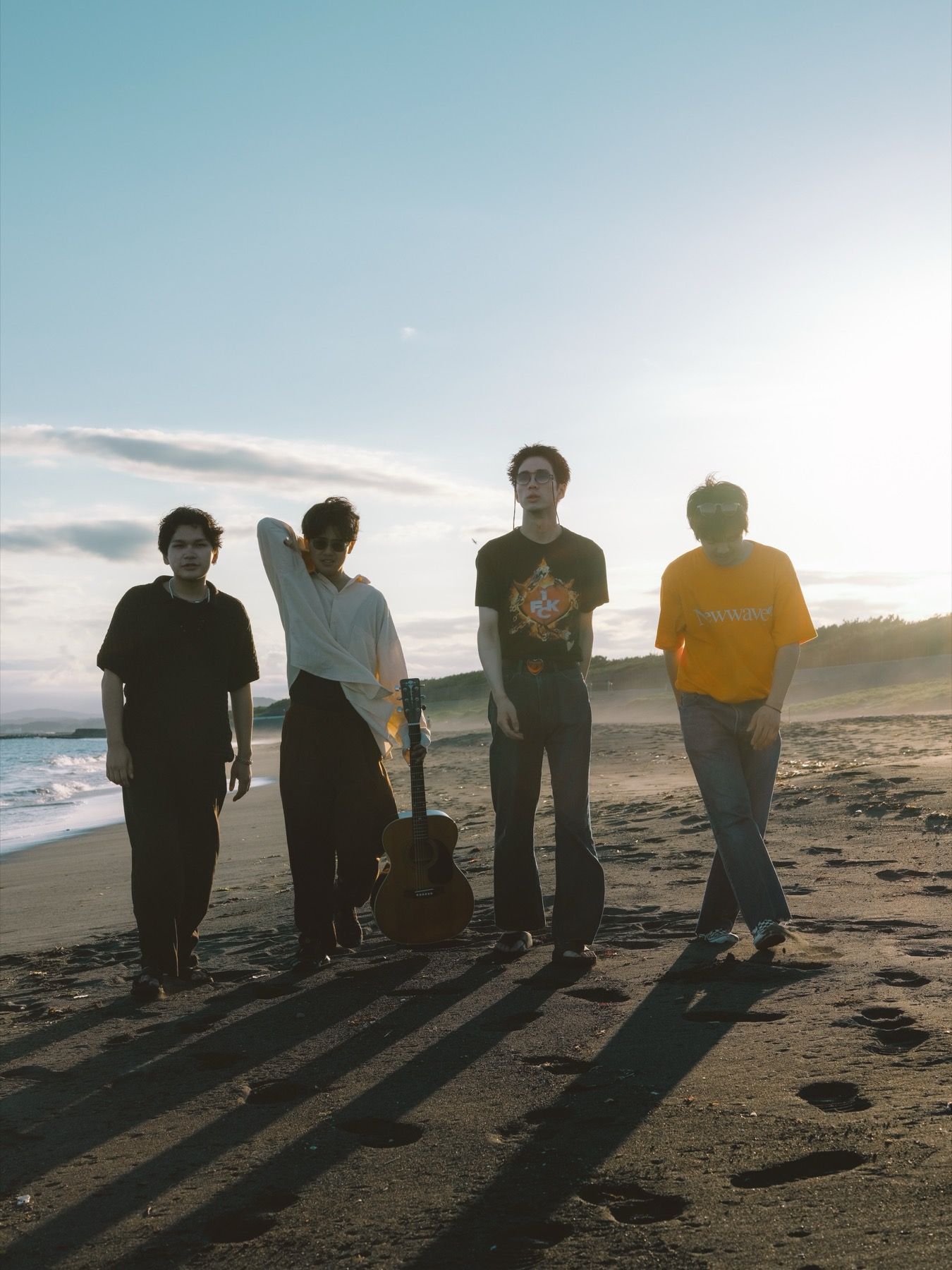 TAKAHASHI LAB — four people walking on a beach in low backlit sun, one carrying an acoustic guitar, long shadows across the sand